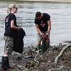 People picking up trash by river
